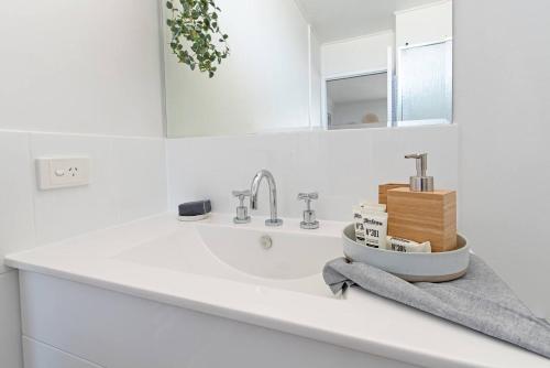 a white bathroom with a sink and a mirror at Scandi Beach Breeze Minutes from Glenelg Beach in Glenelg
