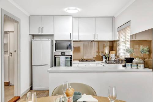 a kitchen with white cabinets and a white refrigerator at Waves and Walks - Close to Beach and Local Boutiques in Adelaide