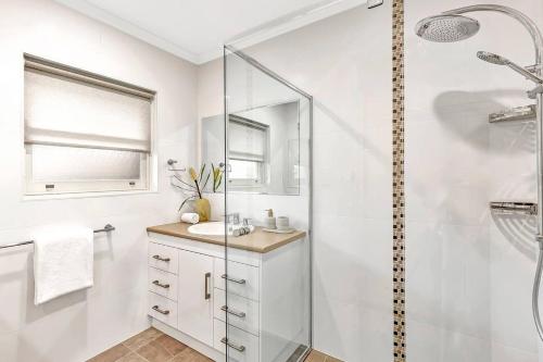 a white bathroom with a shower and a sink at Waves and Walks - Close to Beach and Local Boutiques in Glenelg