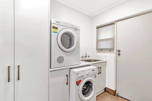 a laundry room with a washing machine and a sink at Waves and Walks - Close to Beach and Local Boutiques in Adelaide