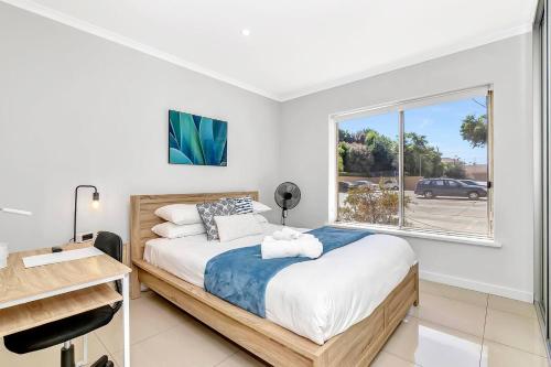 a bedroom with a bed and a window at Coastal Comfort with a Pool opposite Henley Beach in Henley Beach South