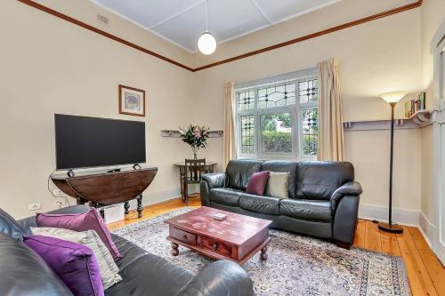 a living room with a couch and a flat screen tv at 'The Nook' Peaceful Toorak Gardens Retro Cottage in Adelaide