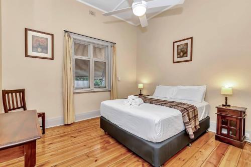 ein Schlafzimmer mit einem Bett und einem Tisch und einem Fenster in der Unterkunft 'The Nook' Peaceful Toorak Gardens Retro Cottage in Adelaide