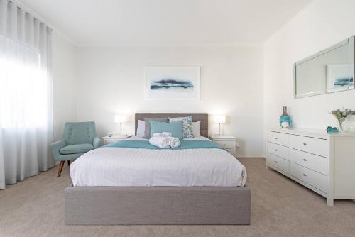 a white bedroom with a large bed and a chair at Colley's Nest - Family-friendly Townhouse with Patio in Adelaide