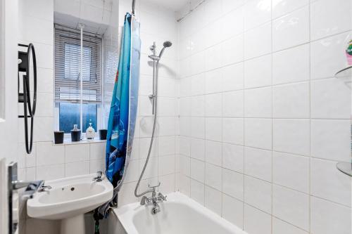 a white bathroom with a tub and a sink at 3 Bedroom Flat Near Finsbury Park, Manor House Station in London