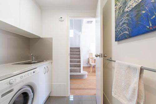 a laundry room with a washer and dryer and a staircase at Colley's Nest - Family-friendly Townhouse with Patio in Adelaide