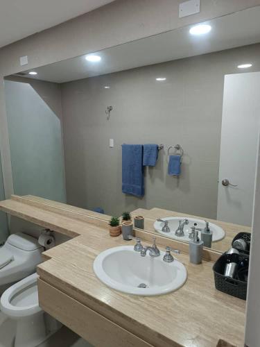 un bagno con lavandino, WC e specchio di Apartahotel a Caracas
