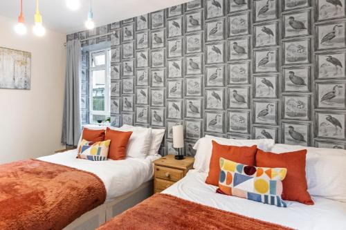 3 Bedroom Flat Near Finsbury Park, Manor House Station في لندن: سريرين في غرفة نوم مع جدار من الصور
