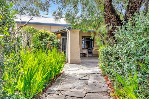 a stone walkway leading to a house with plants at East Parklands Cottage - A Dreamy Garden Hideaway in Adelaide