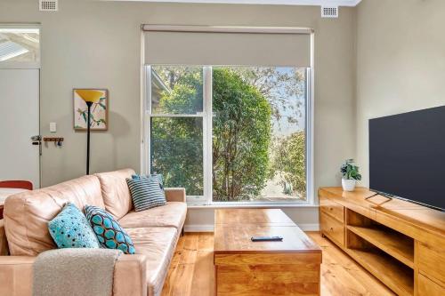 a living room with a couch and a large window at East Parklands Cottage - A Dreamy Garden Hideaway in Adelaide