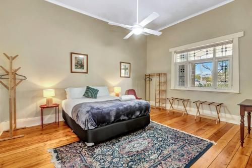 une chambre avec un lit et un ventilateur de plafond dans l'établissement East Parklands Cottage - A Dreamy Garden Hideaway, à Adélaïde