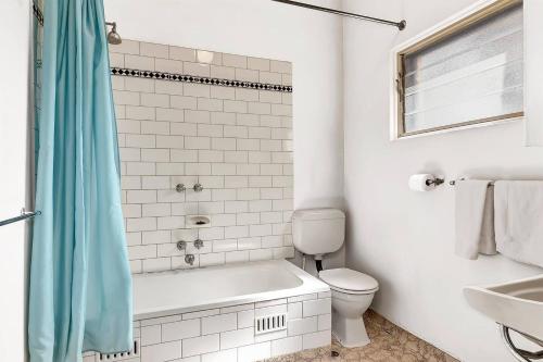 ein Badezimmer mit einer Badewanne, einem WC und einem Waschbecken in der Unterkunft East Parklands Cottage - A Dreamy Garden Hideaway in Rose Park