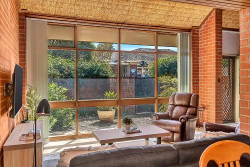 a living room with a couch and a large window at 'The Redstone' Experience Adelaide's Inner-east in Adelaide