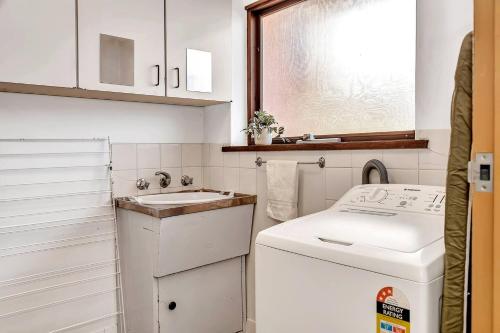 een kleine keuken met een wastafel en een wasmachine bij 'The Redstone' Experience Adelaide's Inner-east in Kensington and Norwood