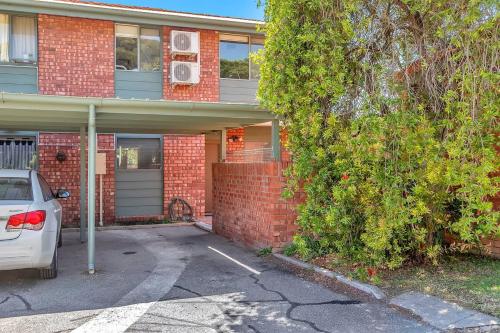 a red brick house with a car parked in the driveway at 'The Redstone' Experience Adelaide's Inner-east in Adelaide