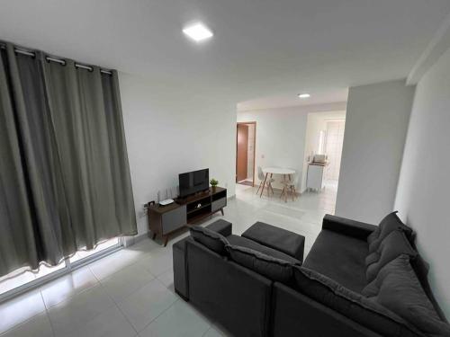 a living room with a black couch and a television at Apartamento 2 quartos in Goiânia