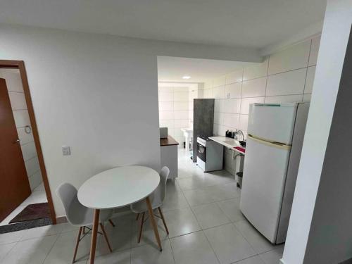 a white kitchen with a table and a refrigerator at Apartamento 2 quartos in Goiânia