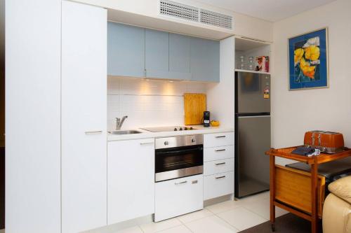 a kitchen with white cabinets and a refrigerator at Little Oak Lodge - Wellness is Calling in Adelaide