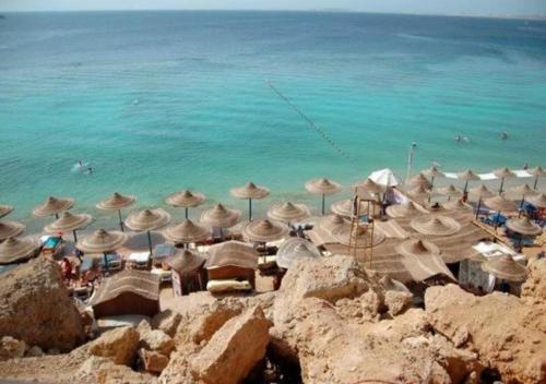 a beach with umbrellas and people in the water at Casa Do Cairo-Sharm Alsheikh in Sharm El Sheikh