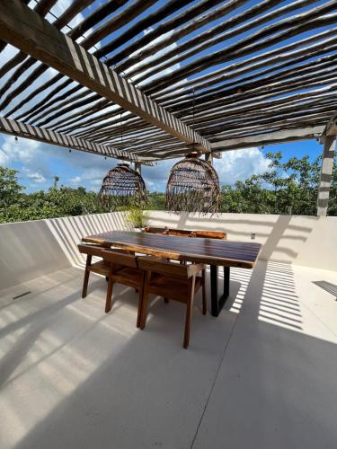 a wooden picnic table under a wooden pergola at Arena Tuane in Tulum