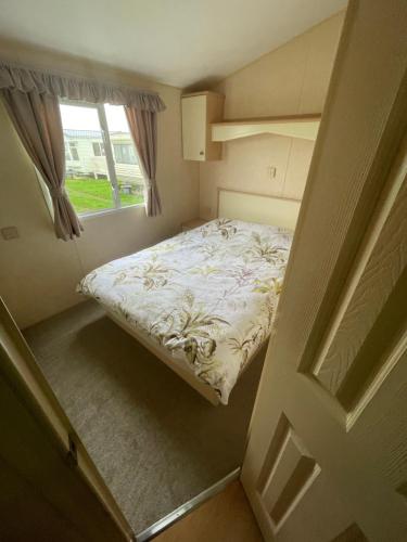 a small bedroom with a bed and a window at Colins Caravan 8berth in Ingoldmells