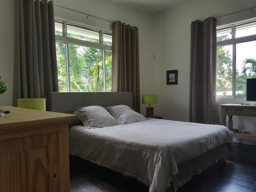 a bedroom with a bed and a large window at Habitation Villa Les Cassias in Petit-Bourg