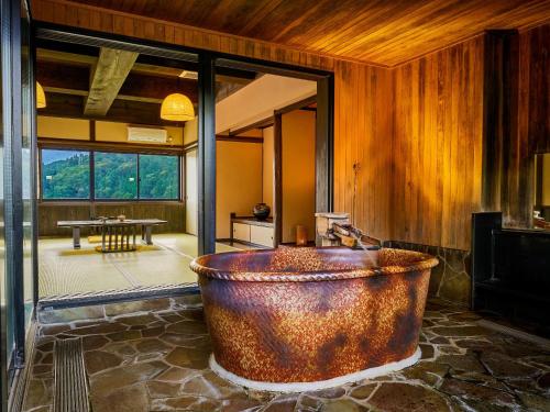 uma grande banheira de cobre num quarto com uma mesa em Yukai Resort Terunoyu em Maniwa