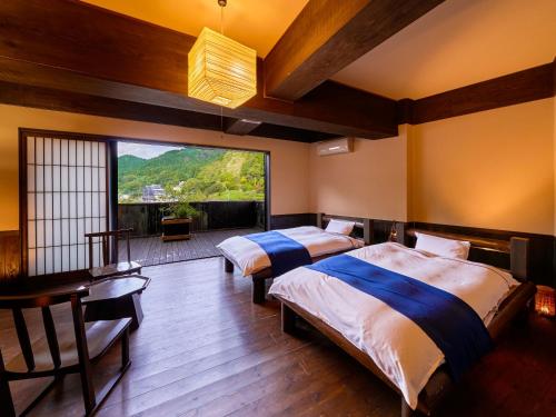 um quarto com 2 camas e uma grande janela em Yukai Resort Terunoyu em Maniwa