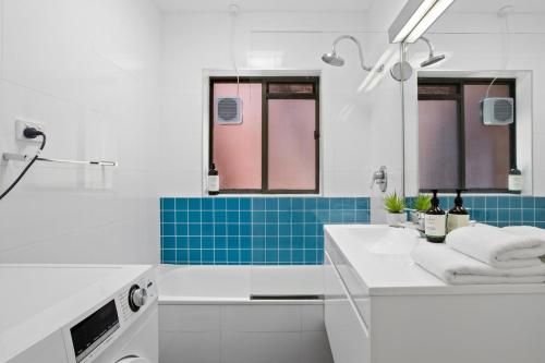 ein weißes Bad mit einem Waschbecken und blauen Fliesen in der Unterkunft The View 2 bed unit with stunning Hobart outlook in Hobart