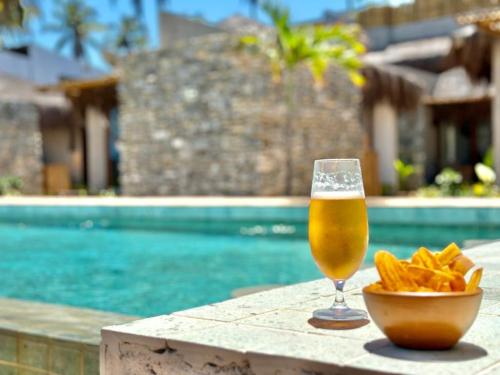 a glass of beer and chips on a table next to a pool at Kuarasy Boutique Hotel Japaratinga in Japaratinga