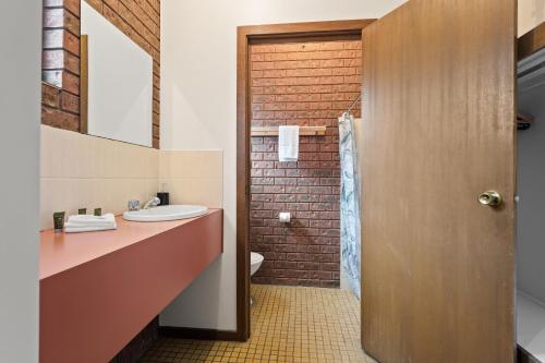 a bathroom with a sink and a brick wall at The Harrietville Snowline Hotel in Harrietville