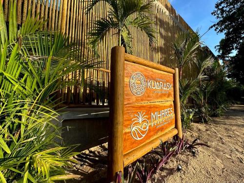 a wooden sign sitting in front of a fence at Kuarasy Boutique Hotel Japaratinga in Japaratinga