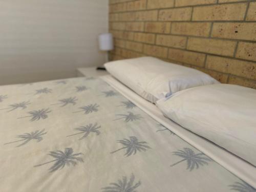 two twin beds in a room with a brick wall at Coolum Budget Accommodation in Coolum Beach