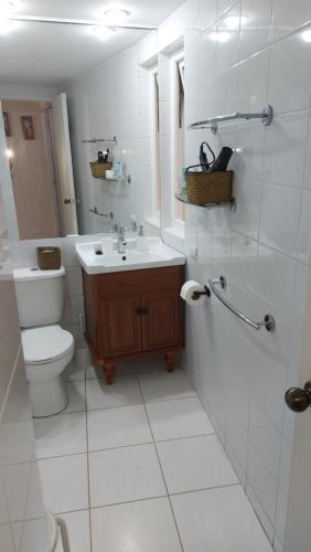 La salle de bains blanche est pourvue de toilettes et d'un lavabo. dans l'établissement Bahia Pelícanos Horcón depto. en primera línea, à Puchuncaví