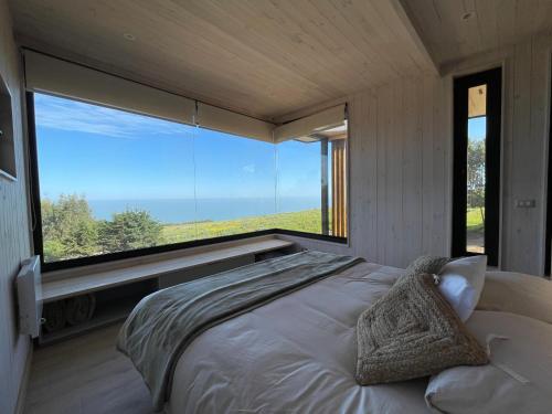 a bed in a room with a large window at Chackra Centinela in Navidad