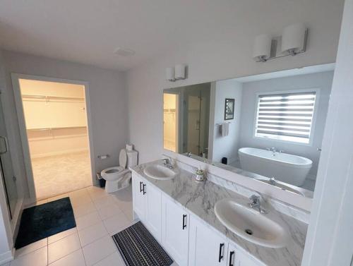 a white bathroom with two sinks and a toilet at Stylish 5-Bedroom Retreat Near Port Dover and Turkey Point Beach in Simcoe