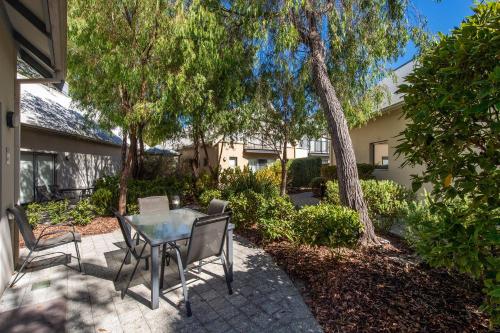 a patio with a table and chairs and trees at Escape to 67 at Cape View in Broadwater