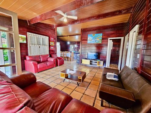 a living room with leather couches and a tv at Chalés Mar Virado in Ubatuba