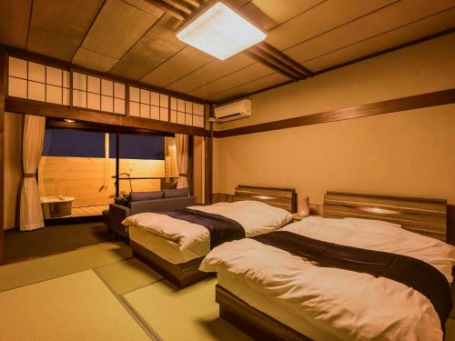 a bedroom with two beds and a window at Yukai Resort Premium NEW MARUYA Hotel in Kaga