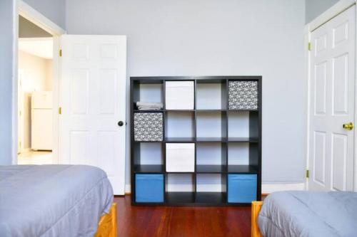 a bedroom with a black book shelf next to two beds at Cozy apartment 3rd 10min Walk Downtown and City View in Providence