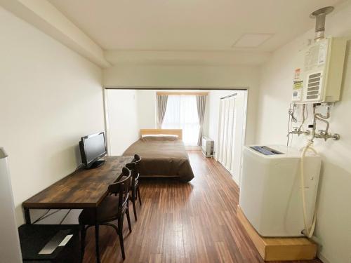 een slaapkamer met een bed, een tafel en een bureau bij ローヤルハイツ菊水駅 in Sapporo