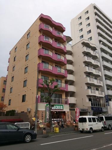 a large apartment building with pink balconies on a city street at ローヤルハイツ菊水駅 in Sapporo