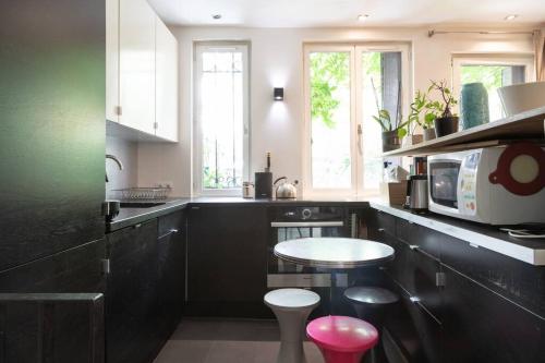 - une cuisine avec des armoires noires et un four micro-ondes blanc dans l'établissement TOWN HOUSE, WITH GARDEN AND PARKING, à Paris