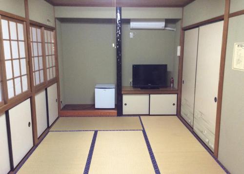 een lege kamer met een televisie en een kamer met een televisie bij Business Hotel Shizusato Ryokan in Ogaki