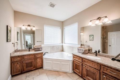 a bathroom with a tub and two sinks and a large mirror at Gorgeous Home w/ Amazing View of Houston Skyline in Houston