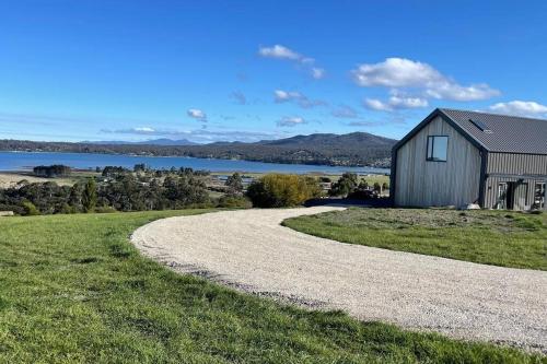a gravel road leading to a building with a lake in the background at The Barn - Georges Bay, St Helens in St Helens