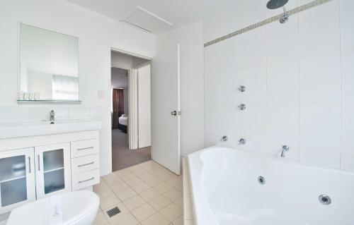 a white bathroom with a tub and a toilet at Nelson Bay Breeze in Nelson Bay