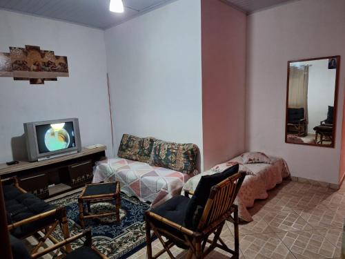 een woonkamer met een bank en een tv bij Casa Bairro Belas Artes in Itanhaém