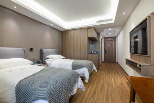 a hotel room with two beds and a flat screen tv at Citadines Zhengda Mall Hefei in Hefei