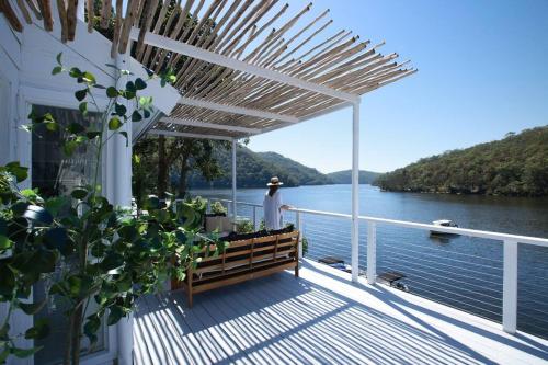 a deck with a bench and a view of the water at rivescape holiday home at Berowra Waters in Berrilee
